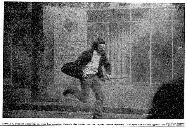 一名学生拿着铁棍在街道上飞奔，眼睛因警方的烟雾弹而紧闭着 NYT 1968.5.30